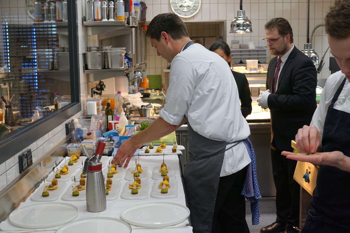 Hannes Graurock beim Feinschliff der Gerichte kurz vor dem Servieren. Sommelier Philippe Schmitz und Restaurantleiterin Tien-San Yap geben die genauen Beschreibungen der Gerichte an die Gäste weiter.