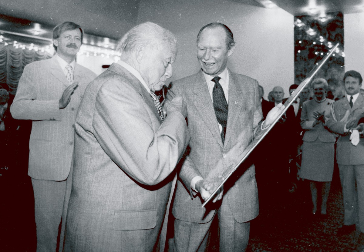 490_008_432518_Jean überrascht Louis Schmit, Oly teilnehmer 1928 mit einem Plakat der ol spiel 1896