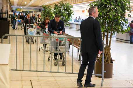 Ein Sicherheitsmitarbeiter achtet darauf, dass nur noch eine begrenzte Anzahl an Kunden in den Gesch&auml;ften anwesend ist. Die Warteschlangen wirken zun&auml;chst abschreckend, doch meist l&ouml;sen sie schon nach kurzer Zeit wieder auf.
