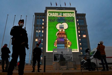 21.10.2020, Frankreich, Montpellier: Polizeibeamte stehen Wache, w&auml;hrend bei einer landesweiten Gedenkveranstaltung an den ermordeten Lehrer Samuel Paty Karikaturen der franz&ouml;sischen Satirezeitung Charlie Hebdo auf die Fassade des Hotel de Region in Montpellier projiziert werden.&nbsp;