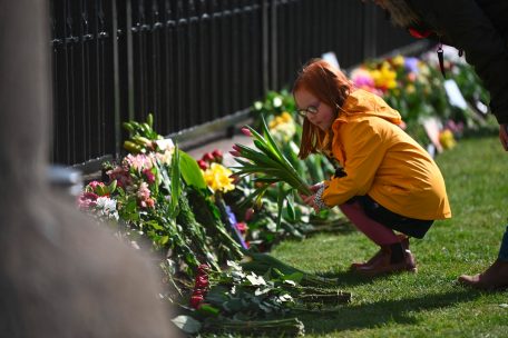 Eine Frau legt Blumen vor Schloss Windsor nieder