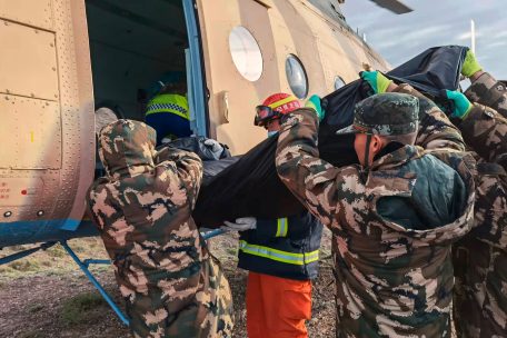Rettungshelfer heben den Leichnam eines Opfers in einen Hubschrauber