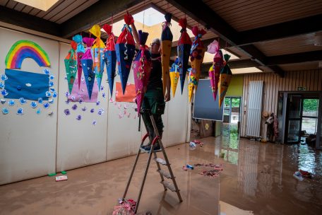 Eine Frau h&auml;ngt im Kindergarten Kordel die an der Decke h&auml;ngenden Schult&uuml;ten ab