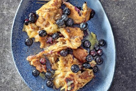 Bei der Kaiserschmarren-Variation von Alex Wahi kommen nach sechs bis sieben Minuten in der Pfanne Blaubeeren auf den Teig. Nach dem Auseinanderzupfen wird Bergkäse über den Kaiserschmarrn gerieben. Ist er geschmolzen, kann serviert werden.