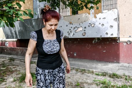 Ukraine, Stepnohirsk: Eine Frau geht an einem mehrst&ouml;ckigen Wohnhaus vorbei, das durch russischen Beschuss besch&auml;digt wurde, in der Region Saporischschja im S&uuml;dosten der Ukraine