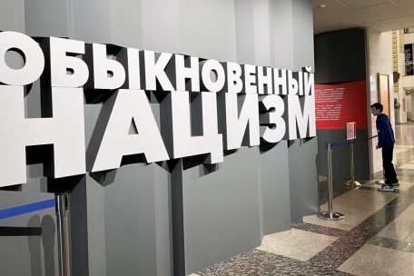 Ein Junge schaut verstohlen in den Ausstellungsraum. Er ist mit &bdquo;Gew&ouml;hnlicher Nazismus&ldquo; &uuml;berschrieben.