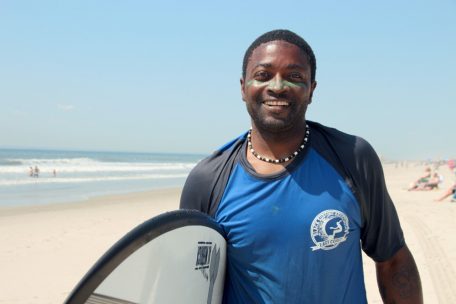 Lou Harris, der Kindern Surfunterricht gibt, steht am Strand.&nbsp;