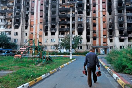 Alltag in der Stadt Irpin: Ein Mann geht auf ein zerschossenes Wohnhaus zu