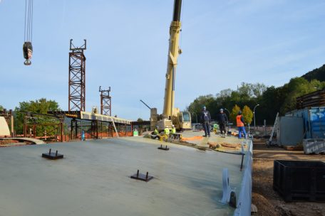 Ist die neue Brücke vor Ort komplett zusammengebaut, wird sie mit Spezialkränen gehievt und auf rollende Untersätze gesetzt