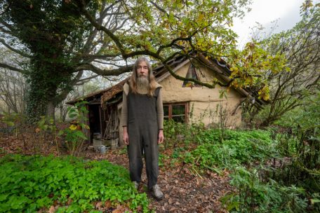 Friedmunt Sonnemann steht am fr&uuml;hen Morgen vor seinem Haus. Seit mehr als drei Jahrzehnten lebt er als Aussteiger in einer selbst gebauten Lehmh&uuml;tte im Wald.