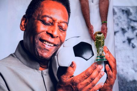 Ein brasilianischer Fan hält eine nachgebildete WM-Trophäe über das Bild des ehemaligen Spielers Pelé