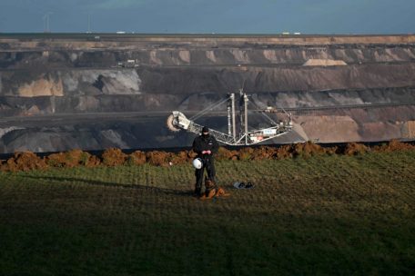 Ein Polizist mit einem Hund steht am 11. Januar 2023 am Rande der Braunkohlegrube im westdeutschen Dorf L&uuml;tzerath