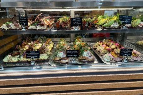 Das Smørrebrød gilt als klassisches Mittagessen. Der Fantasie sind beim Belag der Brotscheibe, meist Roggenbrot, keine Grenzen gesetzt. Diese Variationen sind in der Torvehallerne, einer sogenannten Food Hall, erhältlich. Daneben werden in der Markthalle etliche Fischsorten, Gewürze und Snacks angeboten. Bei der Getränkewahl schwört der Däne auf sein kaltes Bier.