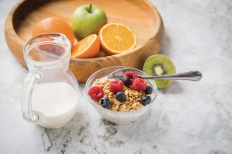 Ein Schälchen Müsli mit Milch und Beeren am Morgen bietet einen guten Start und die erste Portion Selbstfürsorge am Tag 