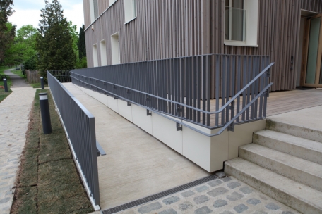 Eine langgezogene Rampe gew&auml;hrleistet barrierefreien Zugang zum Geb&auml;ude
