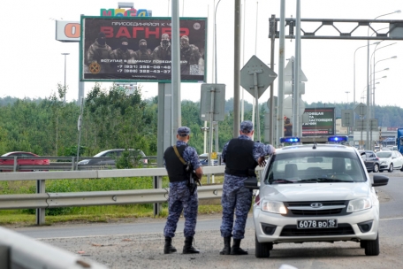 Polizisten bewachen einen Bereich vor einem Plakat, das mit dem Eigentümer der privaten Söldnergruppe Wagner, Prigoschin, in Verbindung gebracht wird