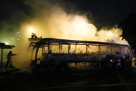 Eine Einsatzkraft der Feuerwehr benutzt einen Wasserschlauch an einem brennenden Bus in Nanterre, außerhalb von Paris.