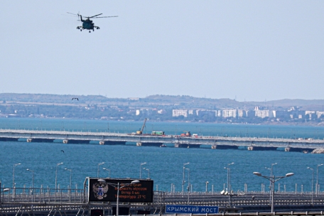 Ein russischer Militärhubschrauber überfliegt über der Straße von Kertsch unweit der Stadt Kertsch auf der Krim die beschädigten Teile einer Automobilverbindung der Krim-Brücke, die das russische Festland mit der Halbinsel verbindet