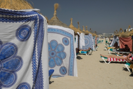 Menschen schützen sich bei hohen Temperaturen mit Strandtüchern vor der Sonne am Strand von Arenal, Mallorca