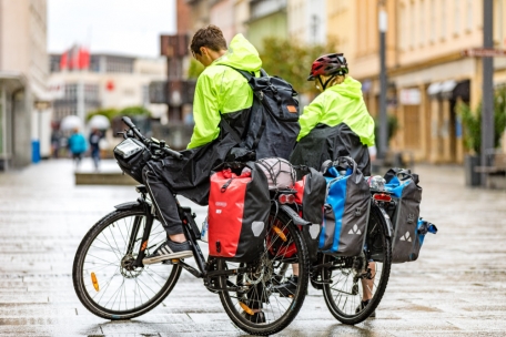 Zwei Radtouristen stehen am 6. August bei Regen mit ihren Fahrrädern in der Cottbuser Fußgängerzone